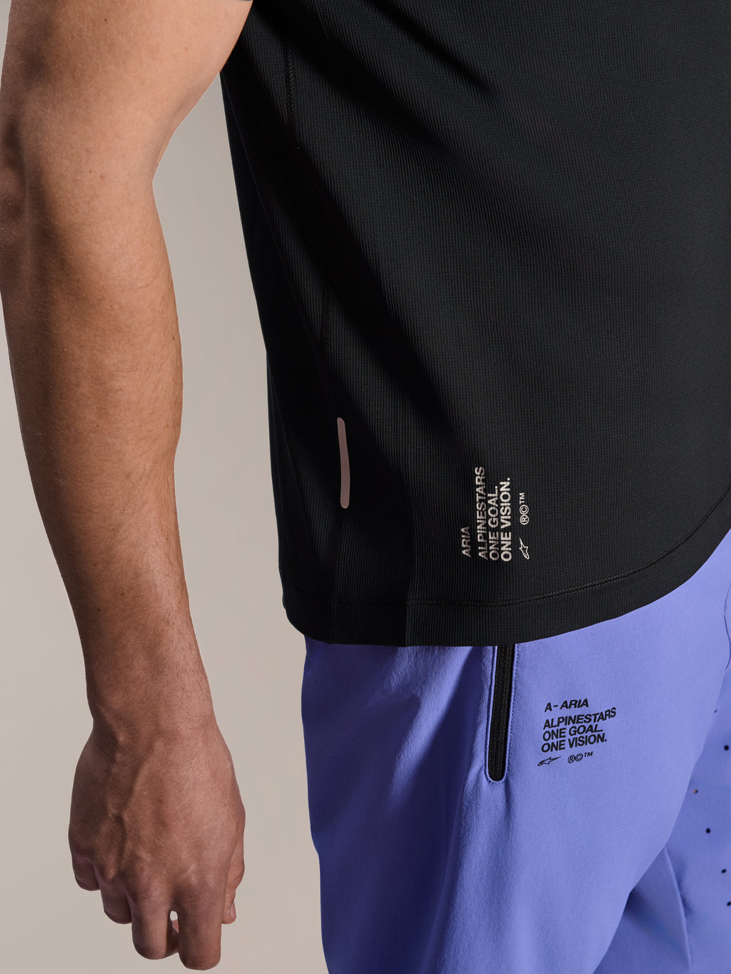 Alpinestars A-Aria Lite Short in Baja Blue, MTB-short, voorzien van gezeefdrukte 'One Goal. One Vision.' branding en zak met ritssluiting, gecombineerd met een zwart A-Aria Switch jersey, close-up van technische fietskleding.
