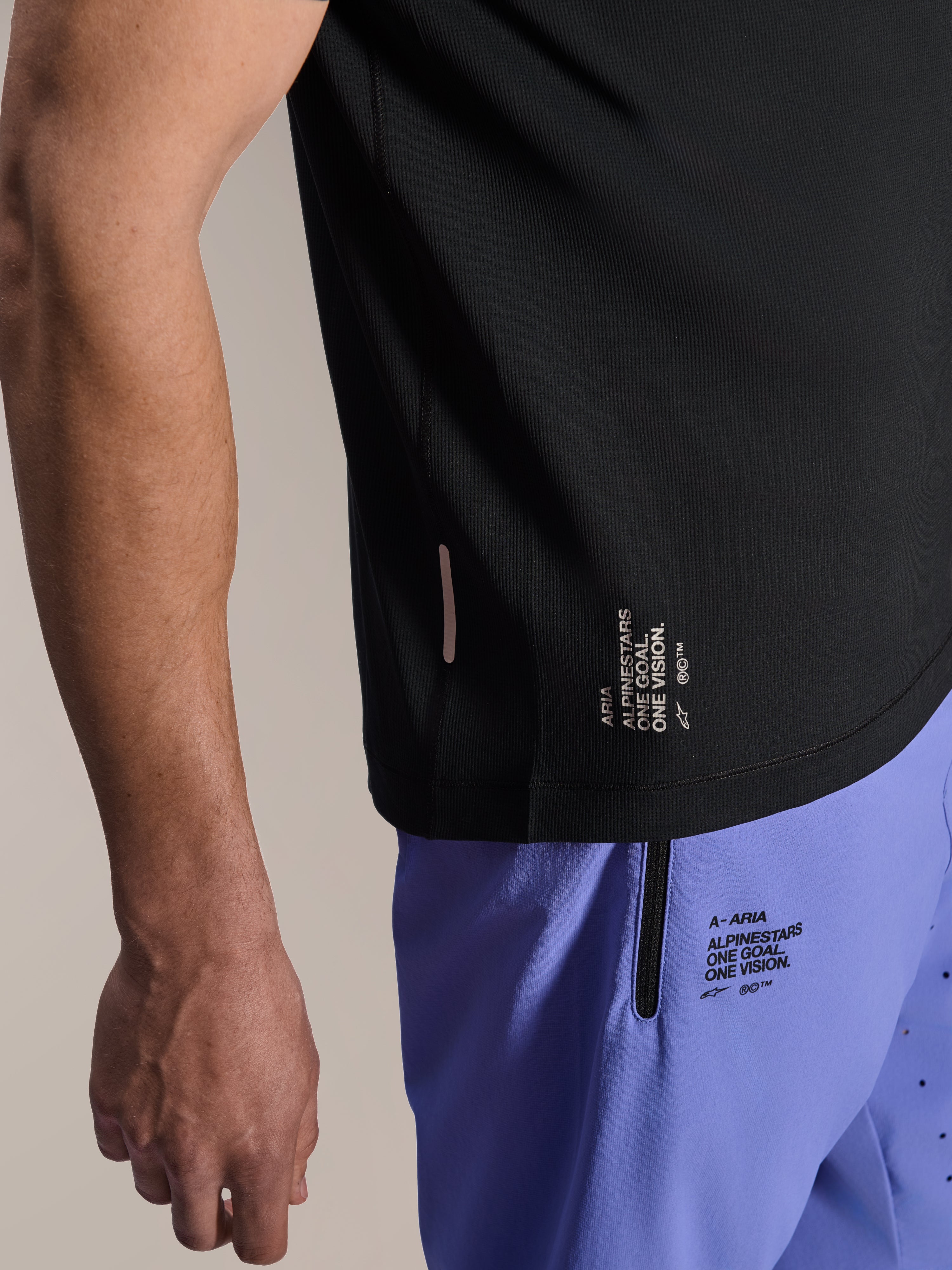 Alpinestars A-Aria Lite Short in Baja Blue, MTB-short, voorzien van gezeefdrukte 'One Goal. One Vision.' branding en zak met ritssluiting, gecombineerd met een zwart A-Aria Switch jersey, close-up van technische fietskleding.