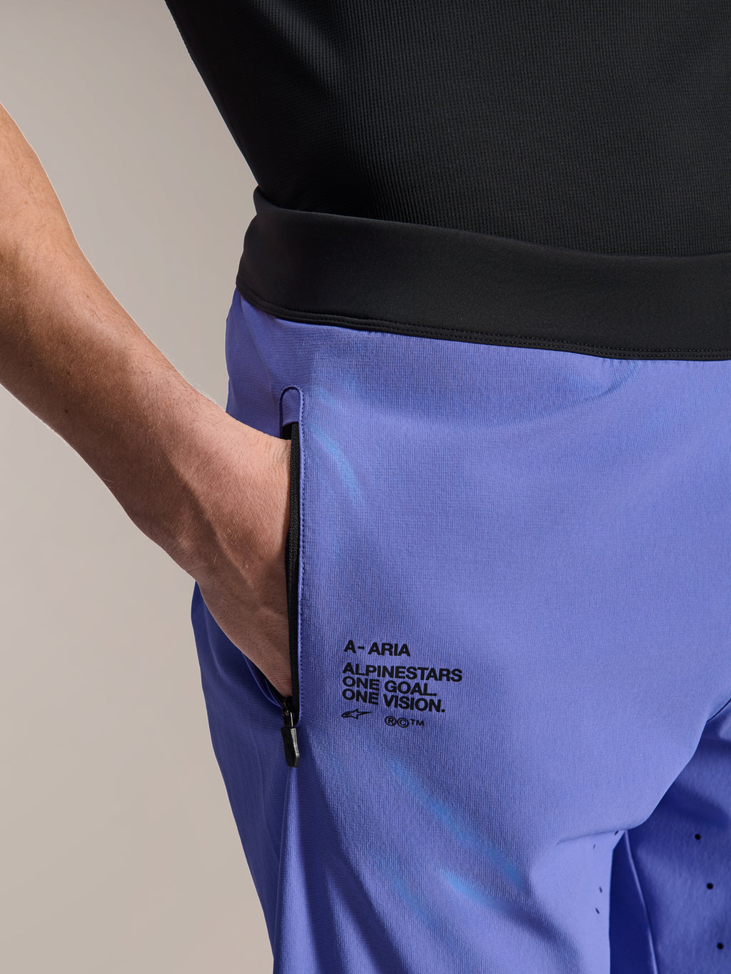 Alpinestars A-Aria Lite Short, MTB-short, Baja Blue, close-up van de voorzak met ritssluiting en branding aan de zijkant met de tekst "One Goal. One Vision.", zwarte tailleband en technische stof voor mountainbiken