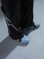 Alpinestars RSRV Starline schoenen, lichtblauwe sneakers met geperforeerde patronen, bruine accenten, wit logo, premium lederen constructie, gedragen met zwarte leren broek met wit ontwerp