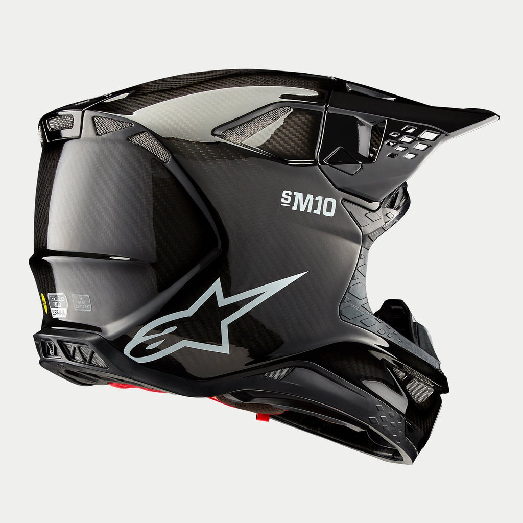 Alpinestars Supertech M10 Solid Helm, motorcrosshelm, zwart glanzende carbon afwerking, voorzien van wit Astars-logo en S-M10-branding, aerodynamische schaal met zichtbaar koolstofvezelweefsel en meerdere ventilatieopeningen.