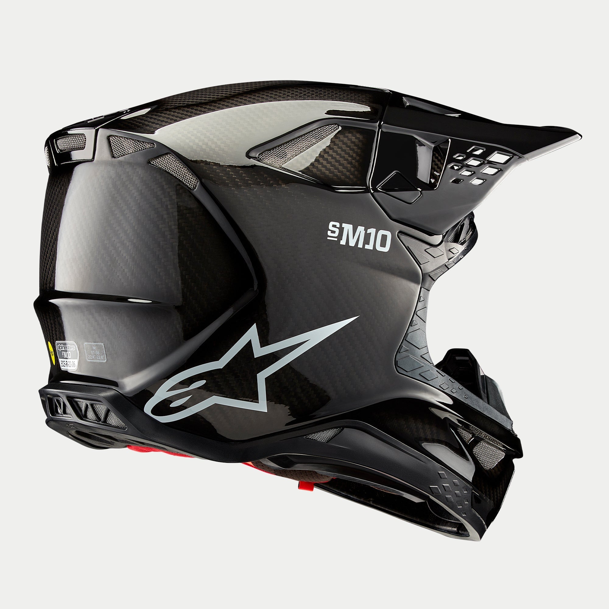 Alpinestars Supertech M10 Solid Helm, motorcrosshelm, zwart glanzende carbon afwerking, voorzien van wit Astars-logo en S-M10-branding, aerodynamische schaal met zichtbaar koolstofvezelweefsel en meerdere ventilatieopeningen.