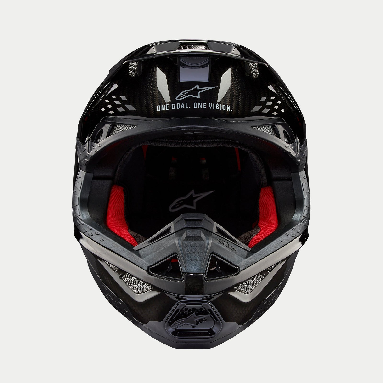 Alpinestars Supertech M10 Solid Helmet, Motocross Helmet, Black Glossy Carbon, front view showing red interior lining, carbon fiber shell, and "ONE GOAL. ONE VISION." slogan on the visor area