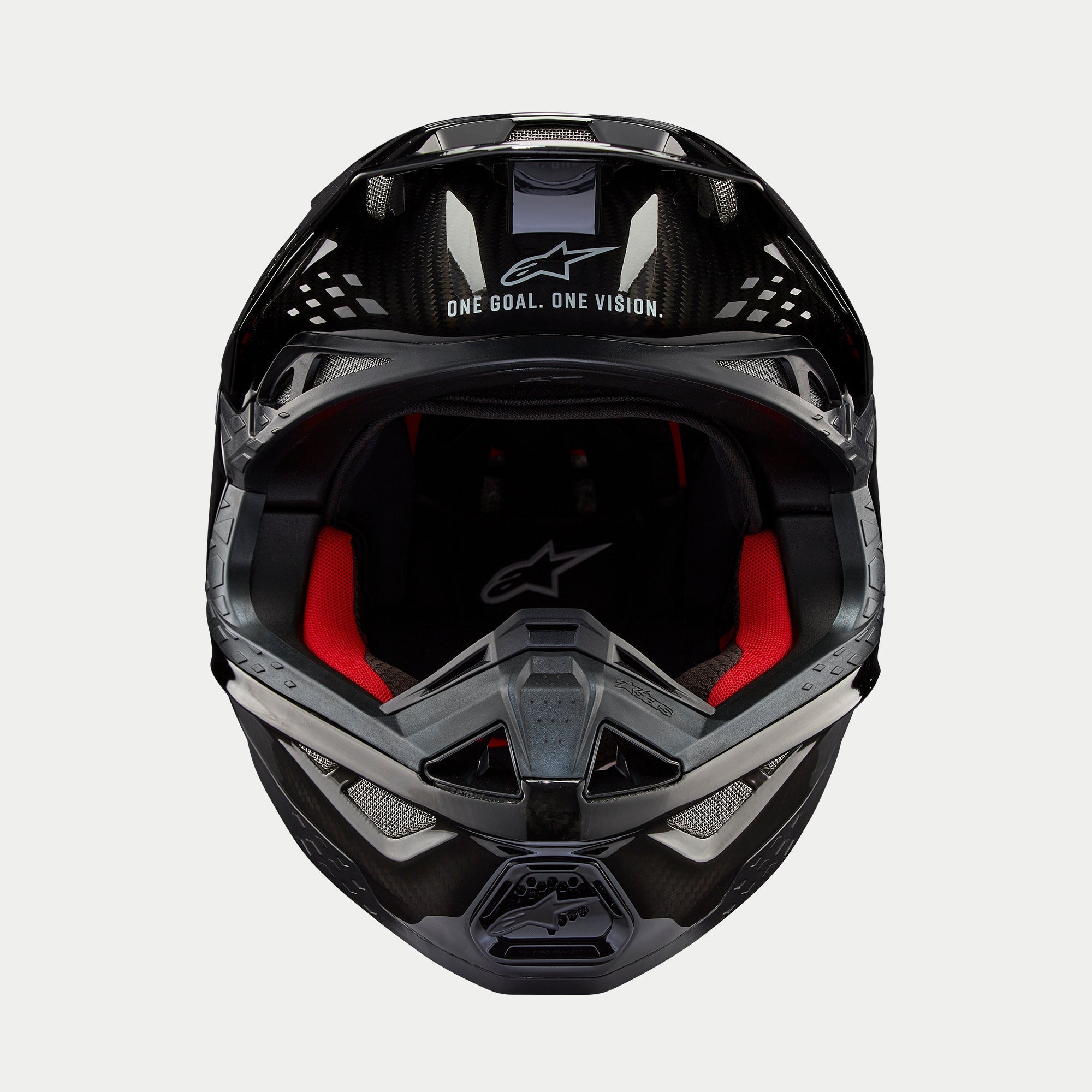 Alpinestars Supertech M10 Solid helm, motorcrosshelm, glanzend zwart carbon, vooraanzicht met rode binnenvoering, koolstofvezel helmschaal en 'ONE GOAL. ONE VISION.' slogan op het viziergedeelte