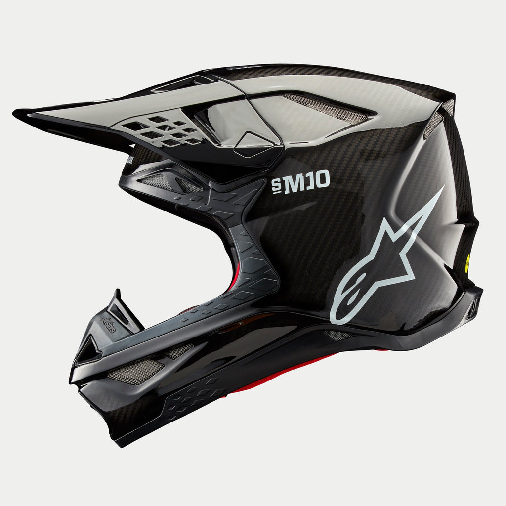 Alpinestars Supertech M10 Solid helm, motorcrosshelm, zwart glanzend carbon, zijprofiel met zichtbaar carbonweefsel, wit SM10-logo en Alpinestars-logo, gestroomlijnd aerodynamisch ontwerp met ventilatieopeningen bedekt met gaas