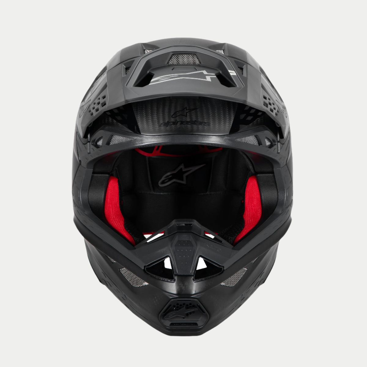 Alpinestars Supertech M10 Fame ECE 22.06 helm, motorcrosshelm, zwart carbon mat en glanzend, vooraanzicht met zichtbare rode binnenvoering, aerodynamische koolstofvezel schaal, geventileerd ontwerp voor off-road racen