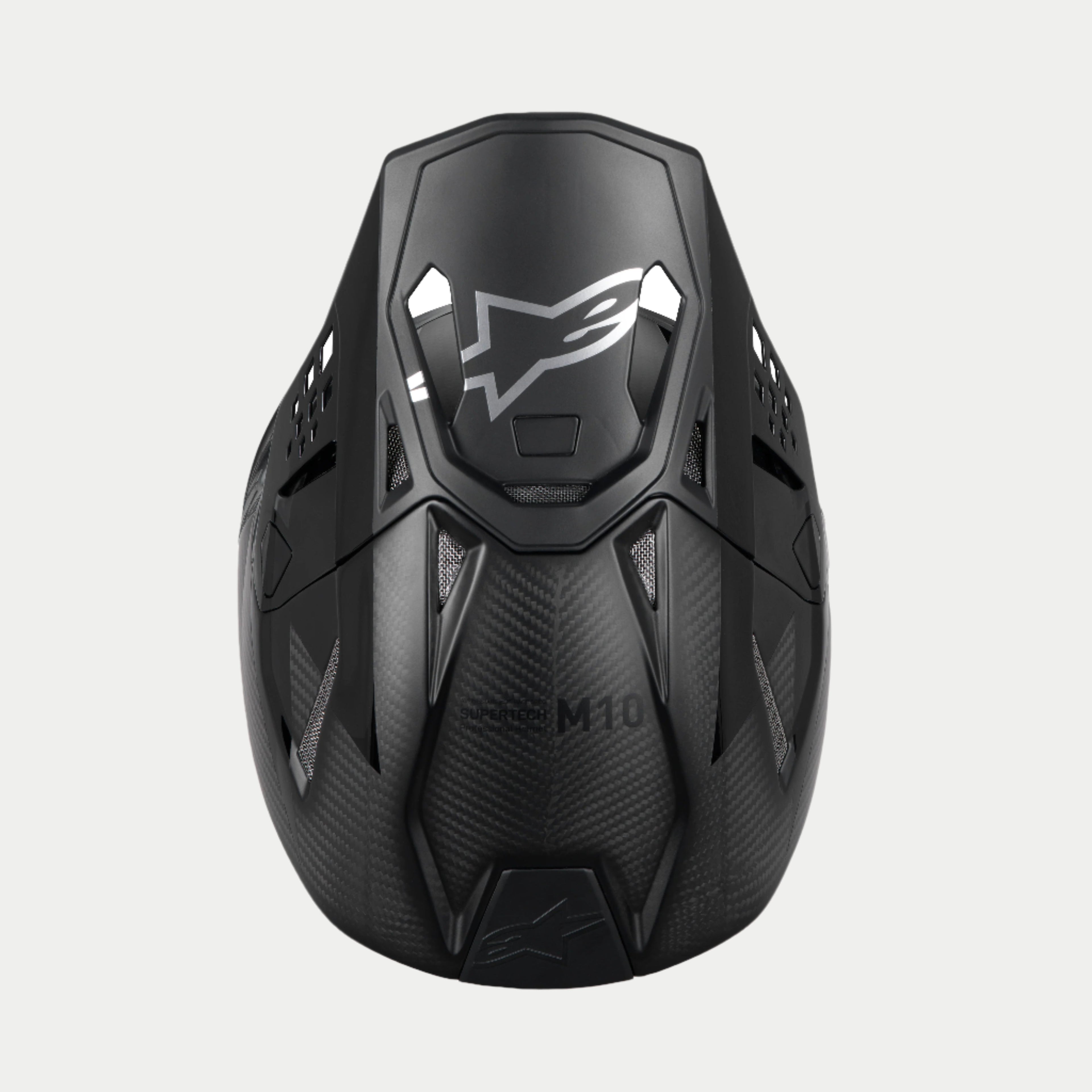 Alpinestars Supertech M10 Fame ECE 22.06 helm, motorcrosshelm, zwart carbon mat en glanzend, bovenaanzicht dat de carbonvezelstructuur benadrukt, aerodynamisch vizier met zilveren Alpinestars-logo en meerdere ventilatiepoorten voor off-road racen.