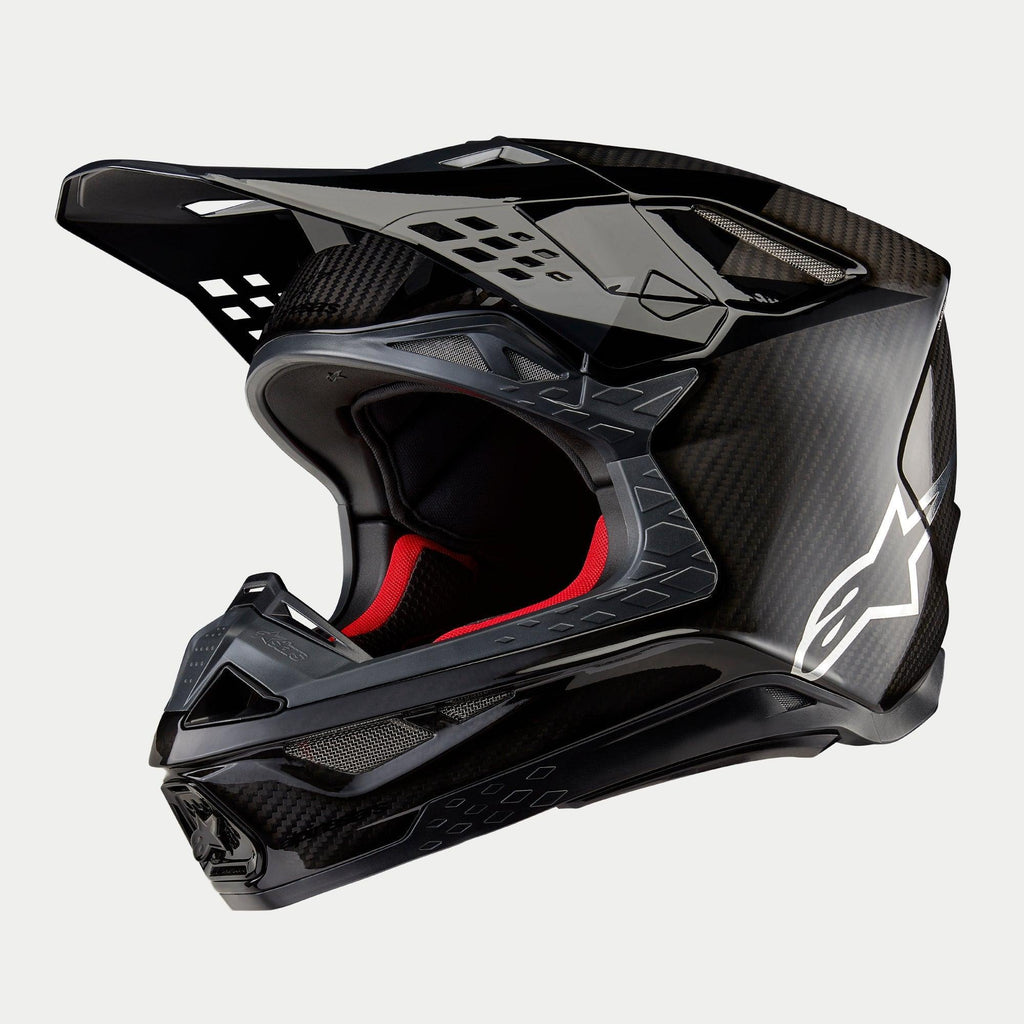 Alpinestars Supertech M10 Fame ECE 22.06 helm, motorcrosshelm, zwarte carbon mat en glanzende afwerking met zichtbare koolstofvezelstructuur, wit Astar-logo op de zijkant en rode binnenvoering, aerodynamisch off-road ontwerp
