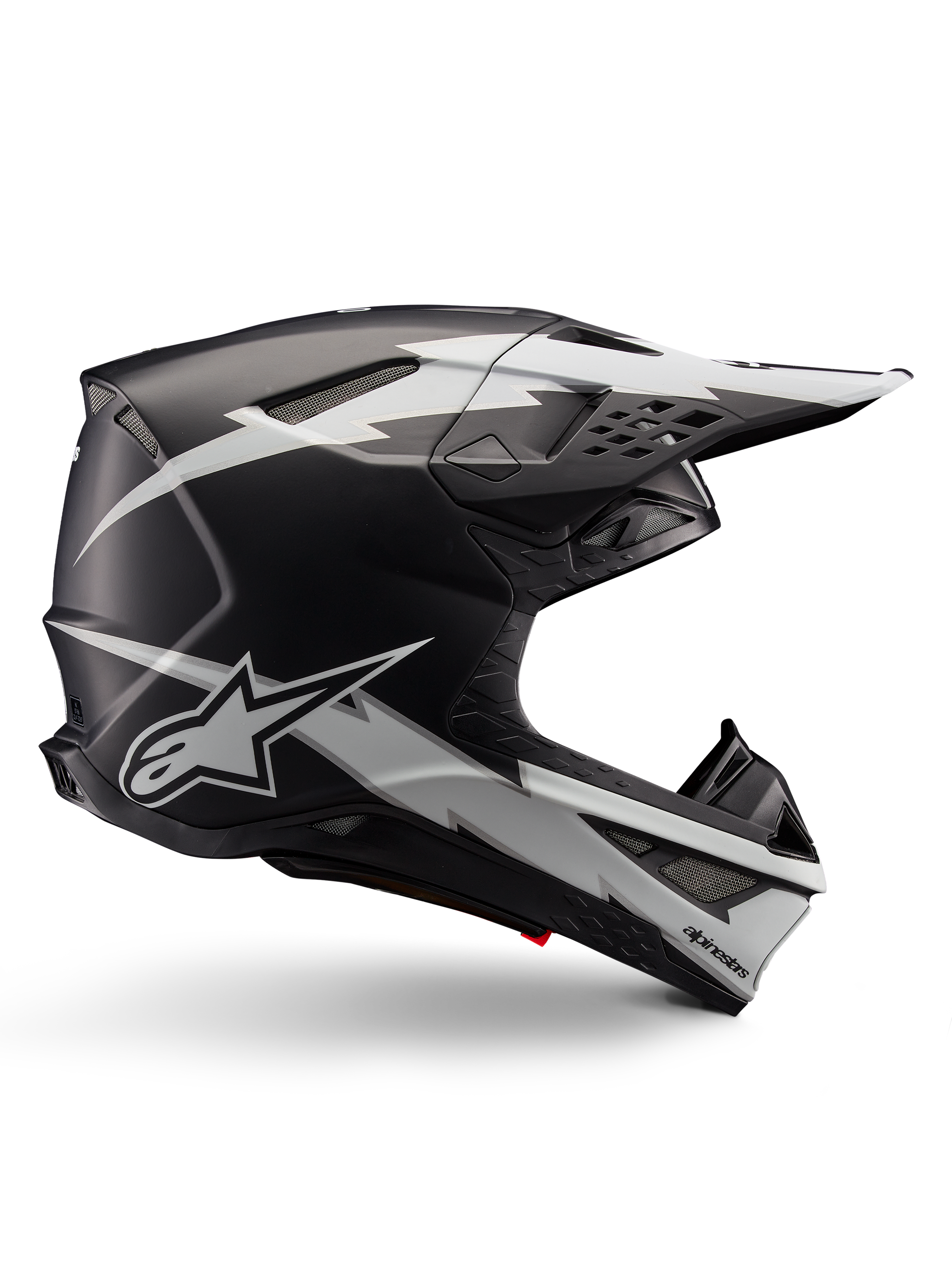 Alpinestars Supertech M10 Ampress helm, motorcross racehelm, zwart en wit mat, aerodynamisch profiel met witte bliksemschicht graphics, meerdere ventilatieopeningen, verlengde zonneklep, carbonfiber constructie met matte afwerking