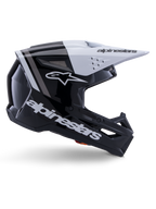 Alpinestars S-M3 Radium helm, motorcross off-road helm, glanzend zwart, wit en grijs, hoekig aerodynamisch ontwerp met ventilatieopeningen, zijaanzicht, glanzende afwerking met grijze strepen en een wit vizier met Alpinestars-branding