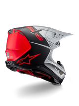 Alpinestars Supertech M10 Flood ECE 22.06 Helm, motorcrosshelm, zilver, zwart en fluo oranje, zij-achteraanzicht met nadruk op het aerodynamische schaalontwerp, ventilatieopeningen en mat-glanzende afwerking