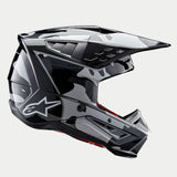 Alpinestars S-M5 Rover 2 Helm ECE, motorcrosshelm, zwart en zilver glanzend, zijprofiel met een camouflage-stijl patroon, voorzien van een aerodynamisch vizier, meerdere ventilatieopeningen en het witte Astars-logo op de zijkant.