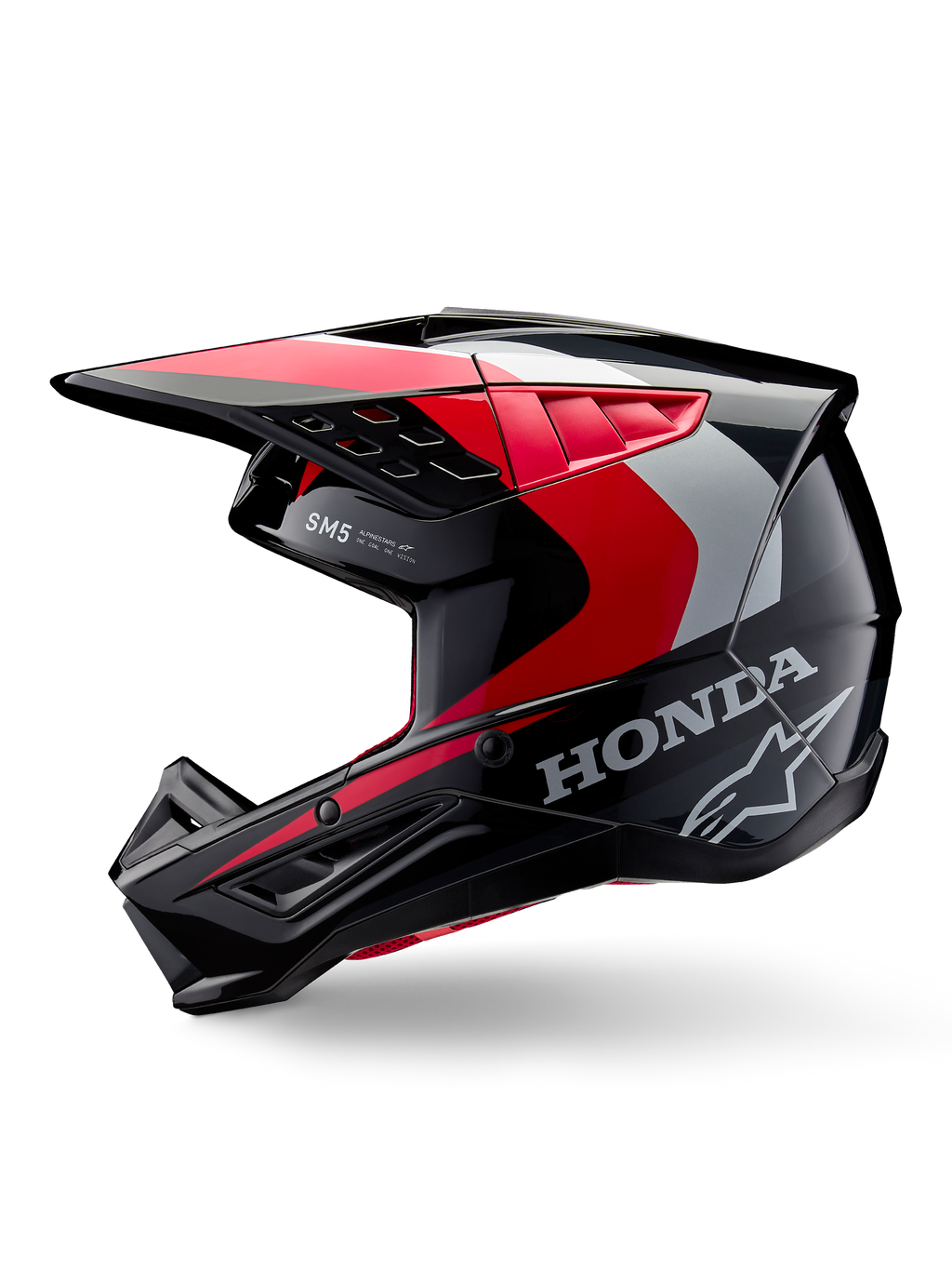 Alpinestars Honda S-M5 helm, motorcrosshelm, glanzend zwart met rode en zilveren accenten, zijaanzicht met Honda-branding en Alpinestars sterlogo, strak ontwerp met geïntegreerde klep en ventilatieopeningen voor off-road prestaties