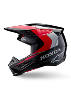 Alpinestars Honda S-M5 helm, motorcrosshelm, glanzend zwart met rode en zilveren accenten, zijaanzicht met Honda-branding en Alpinestars sterlogo, strak ontwerp met geïntegreerde klep en ventilatieopeningen voor off-road prestaties