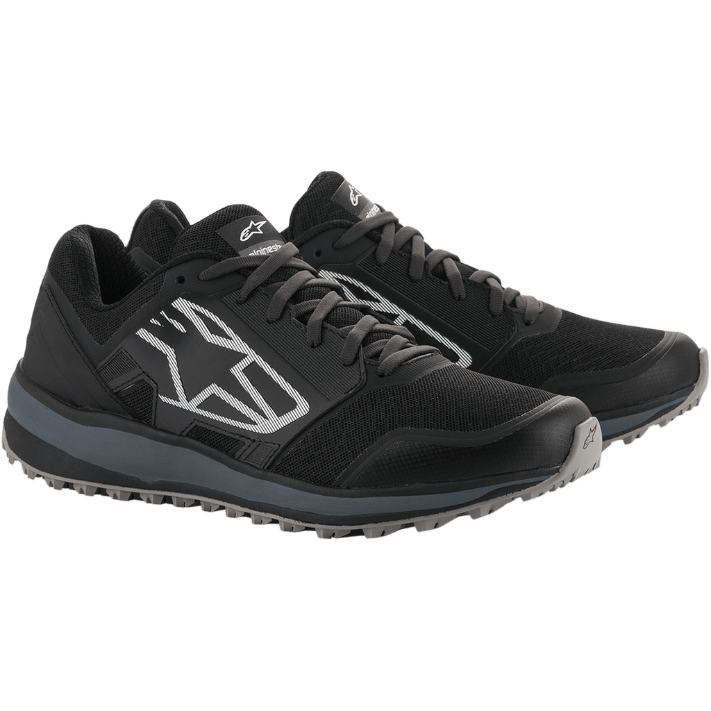 Alpinestars Meta Trail schoenen, prestatie hardloopschoenen, zwart en donkergrijs, groot wit gestreept Astars-logo op de zijkant, vetersluiting met een robuuste grijze zool, ontworpen voor comfort de hele dag door in de paddock