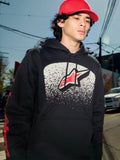 Alpinestars Obsessed Hoodie, zwarte fleece pullover, witte MX-verloop graphic op de borst met rood sterlogo, rode woordmerk-logo's op de mouwen, casual motorsport-geïnspireerde streetwear gedragen in een stedelijke omgeving.