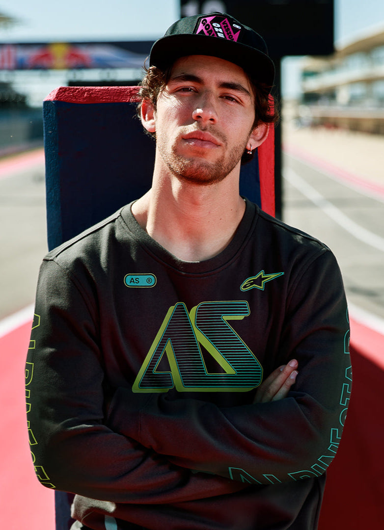 Alpinestars Ayess Csf Tee, T-shirt met lange mouwen, zwart, met groen en geel kleurverloop AS-graphics op de borst en mouwen, casual op motorsport geïnspireerde streetwear gedragen op een circuit.