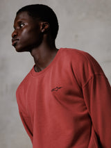 Alpinestars Essentials Ageless Crew, steenrood crewneck sweatshirt, gedragen door een mannelijk model in zijprofiel, klein zwart sterlogo op de borst, ontspannen pasvorm, premium fleece casual streetwear
