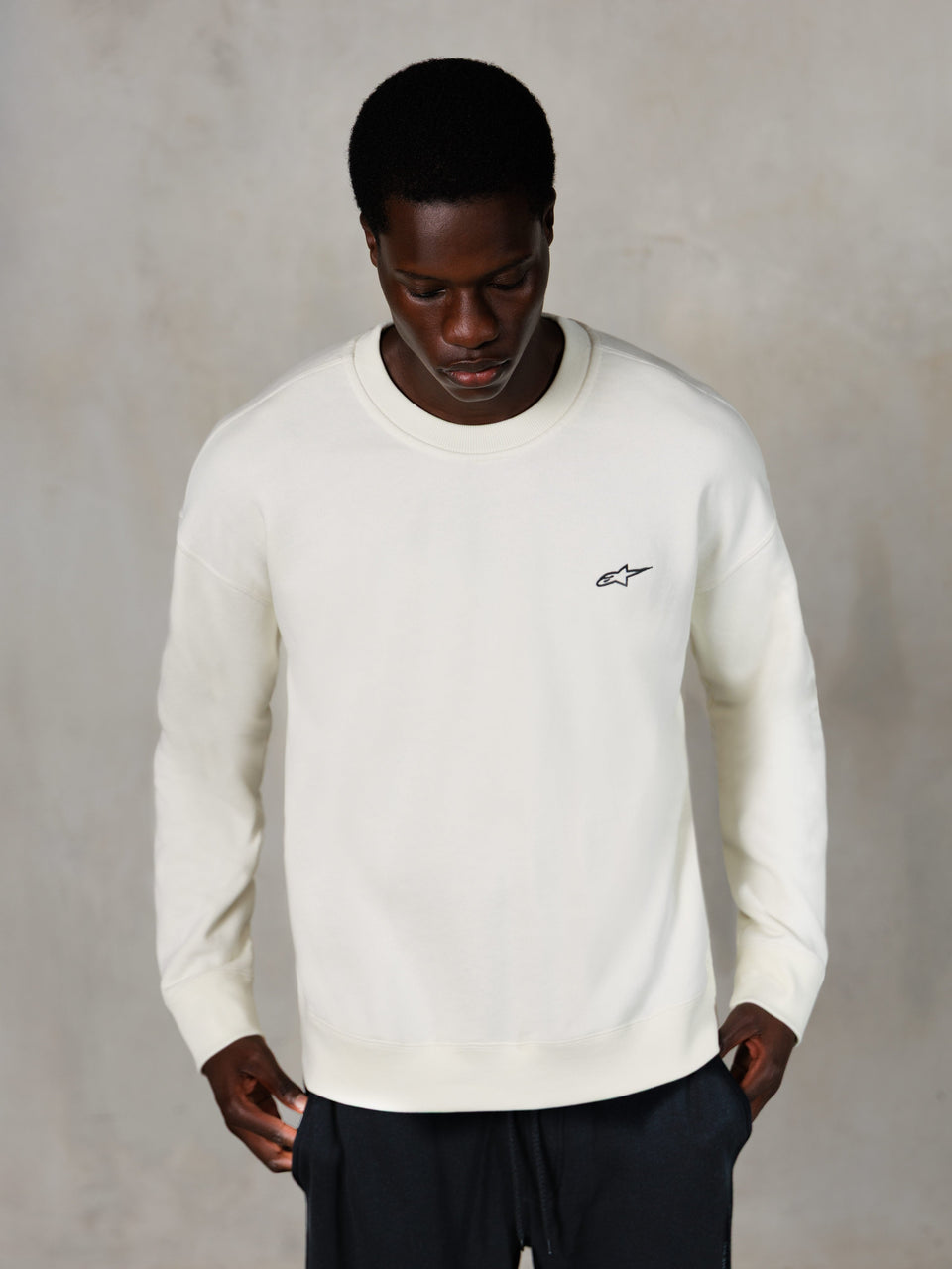 Alpinestars Essentials Ageless Crew, crewneck sweatshirt, off-white, klein zwart Alpinestars-logo op de borst, gedragen door model, casual lifestyle streetwear, premium zachte fleece