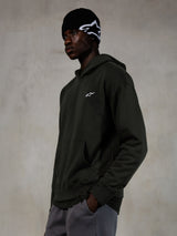 Alpinestars Essentials Ageless Hoodie, Off Black, mannelijk model in casual streetwear, donker antraciet stone-washed fleece met een klein wit ster-logo, gecombineerd met een zwarte Alpinestars beanie en een grijze broek