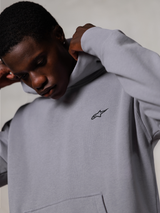 Alpinestars Essentials Ageless Hoodie, Silver, close-up of a man adjusting the hood of the grey sweatshirt, small black Alpinestars logo on the chest, premium motorsport-inspired casual wear
