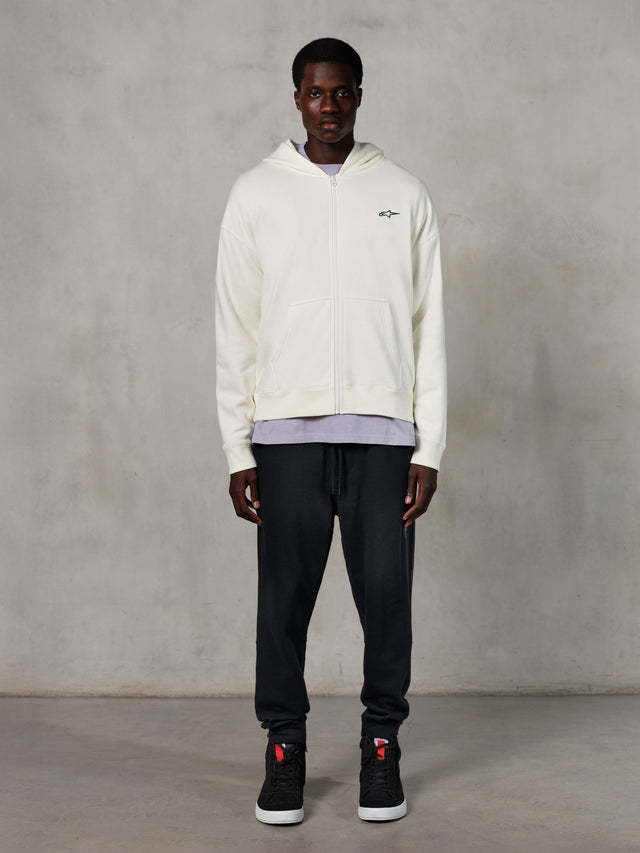 Alpinestars Essentials Ageless Zip Hoodie, casual streetwear, off-white met subtiel zwart borstlogo, volledige ritssluiting aan de voorzijde, ontwerp met capuchon, ontspannen pasvorm, gestyled met een zwarte joggingbroek en sneakers