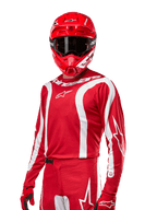 Alpinestars 2024 Fluid Lurv jersey, motorcross shirt, Mars Red en wit, gedragen met bijpassende rode helm en handschoenen, opvallend sportief design met witte gebogen strepen en Alpinestars-branding