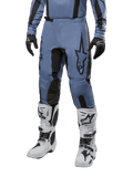 Alpinestars 2024 Fluid Lurv Pants, motorcross broek, lichtblauw en zwart, gedragen met bijpassende jersey met lange mouwen en witte motorcrosslaarzen, voorzien van een prominent zwart sterlogo op de dij en versterkte panelen aan de binnenkant van de knie, vooraanzicht op witte achtergrond