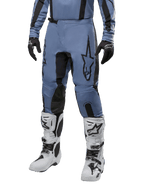 Alpinestars 2024 Fluid Lurv Pants, motorcross broek, lichtblauw en zwart, gedragen met bijpassende jersey met lange mouwen en witte motorcrosslaarzen, voorzien van een prominent zwart sterlogo op de dij en versterkte panelen aan de binnenkant van de knie, vooraanzicht op witte achtergrond