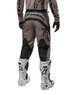 Alpinestars 2024 Fluid Lurv crossbroek, motorcross broek, Mud Black, achteraanzicht met groot zwart Alpinestars-logo op het zitvlak en zwarte kuitpanelen, gedragen met wit-zwarte motorcrosslaarzen en bijpassende jersey.