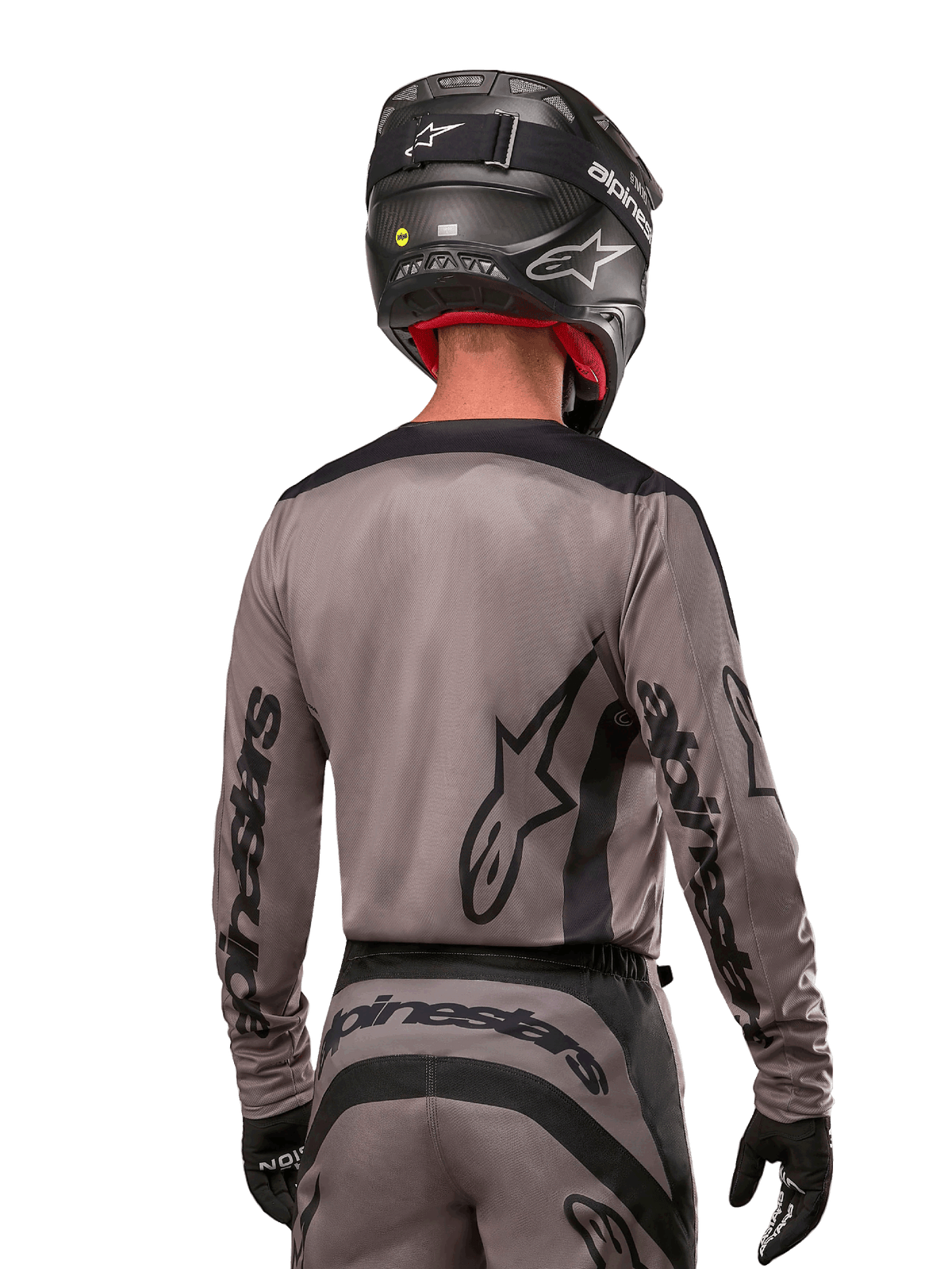 Motorcrossrijder van achteren gezien in de Alpinestars 2024 Fluid Lurv Jersey in Mud Black, met zwarte Alpinestars branding op de mouwen en rug, gecombineerd met een zwarte helm en bijpassende uitrusting voor off-road racen
