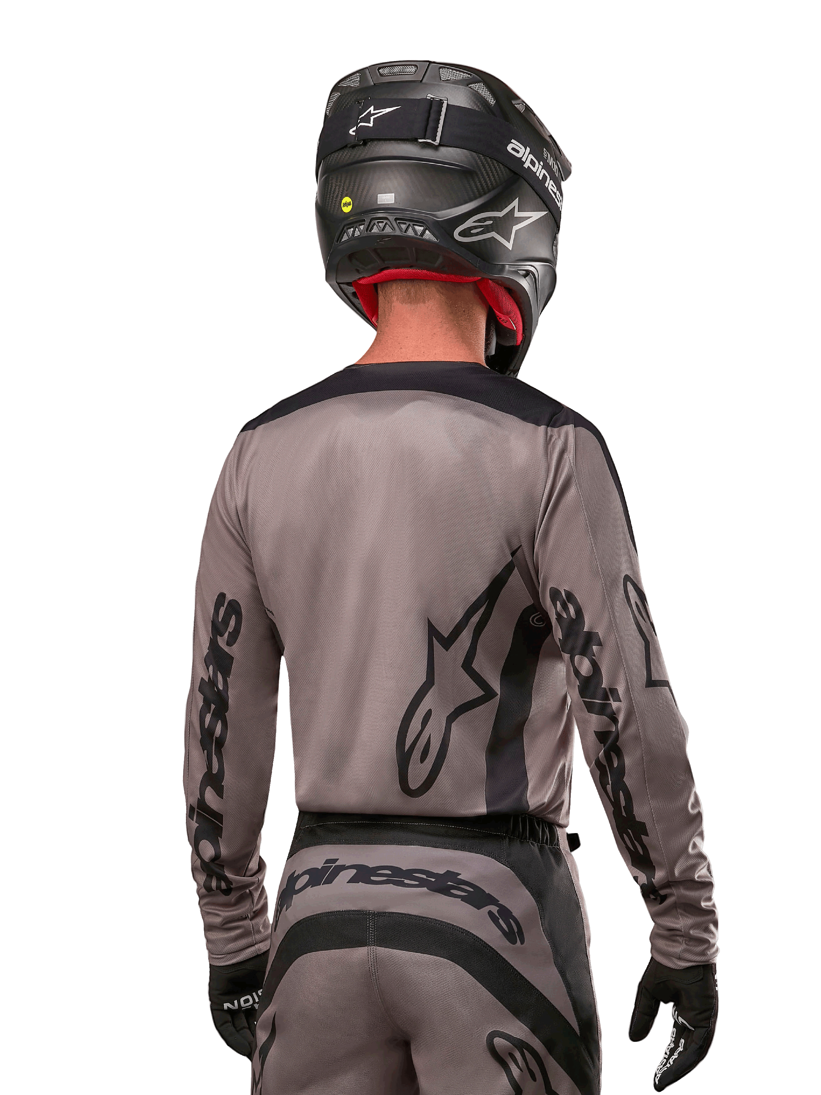 Motorcrossrijder van achteren gezien in de Alpinestars 2024 Fluid Lurv Jersey in Mud Black, met zwarte Alpinestars branding op de mouwen en rug, gecombineerd met een zwarte helm en bijpassende uitrusting voor off-road racen