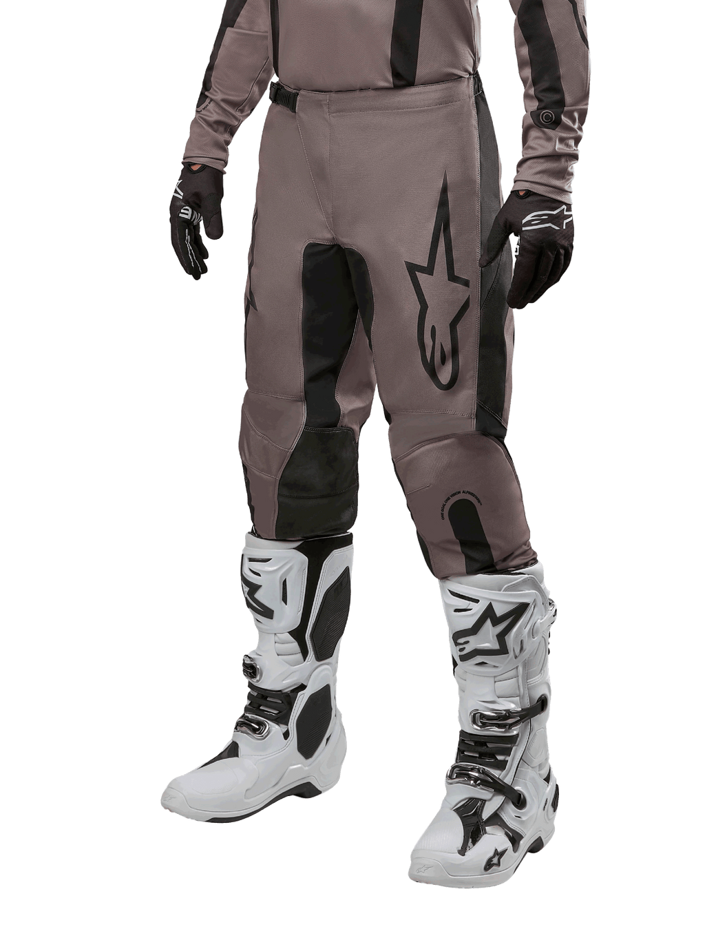 Alpinestars 2024 Fluid Lurv crossbroek, motorcrossbroek, Mud Black en zwart, voorzien van Alpinestars-logo, gedragen met zwarte handschoenen en witte motorcrosslaarzen, sportief ontwerp voor off-road racen