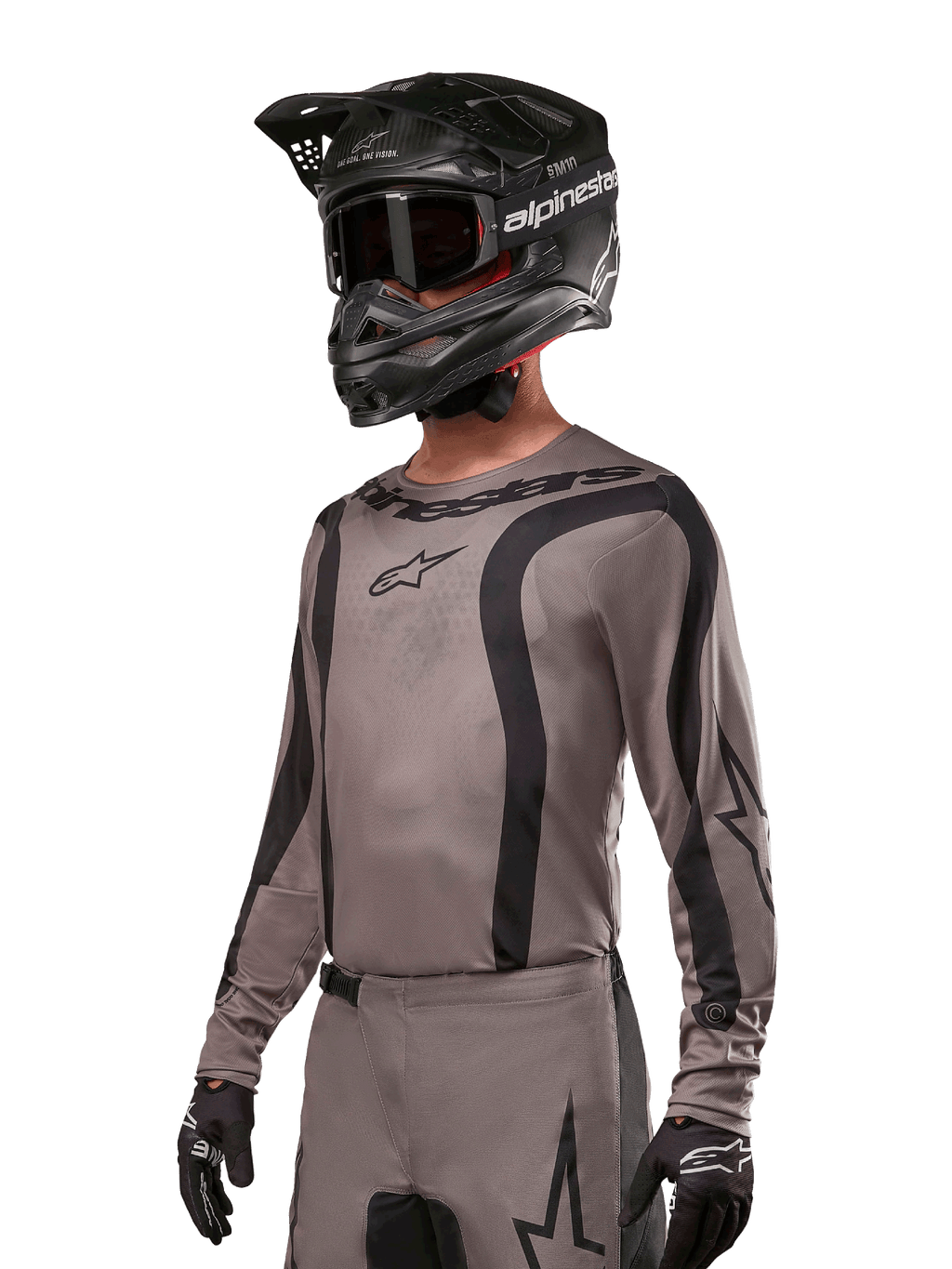 Alpinestars 2024 Fluid Lurv Jersey, motocross shirt, Mud Black en grijs, ontwerp met lange mouwen met gebogen zwarte strepen en logo's, gedragen met bijpassende broek en een zwarte motorcrosshelm, gecoördineerde off-road race-uitrusting