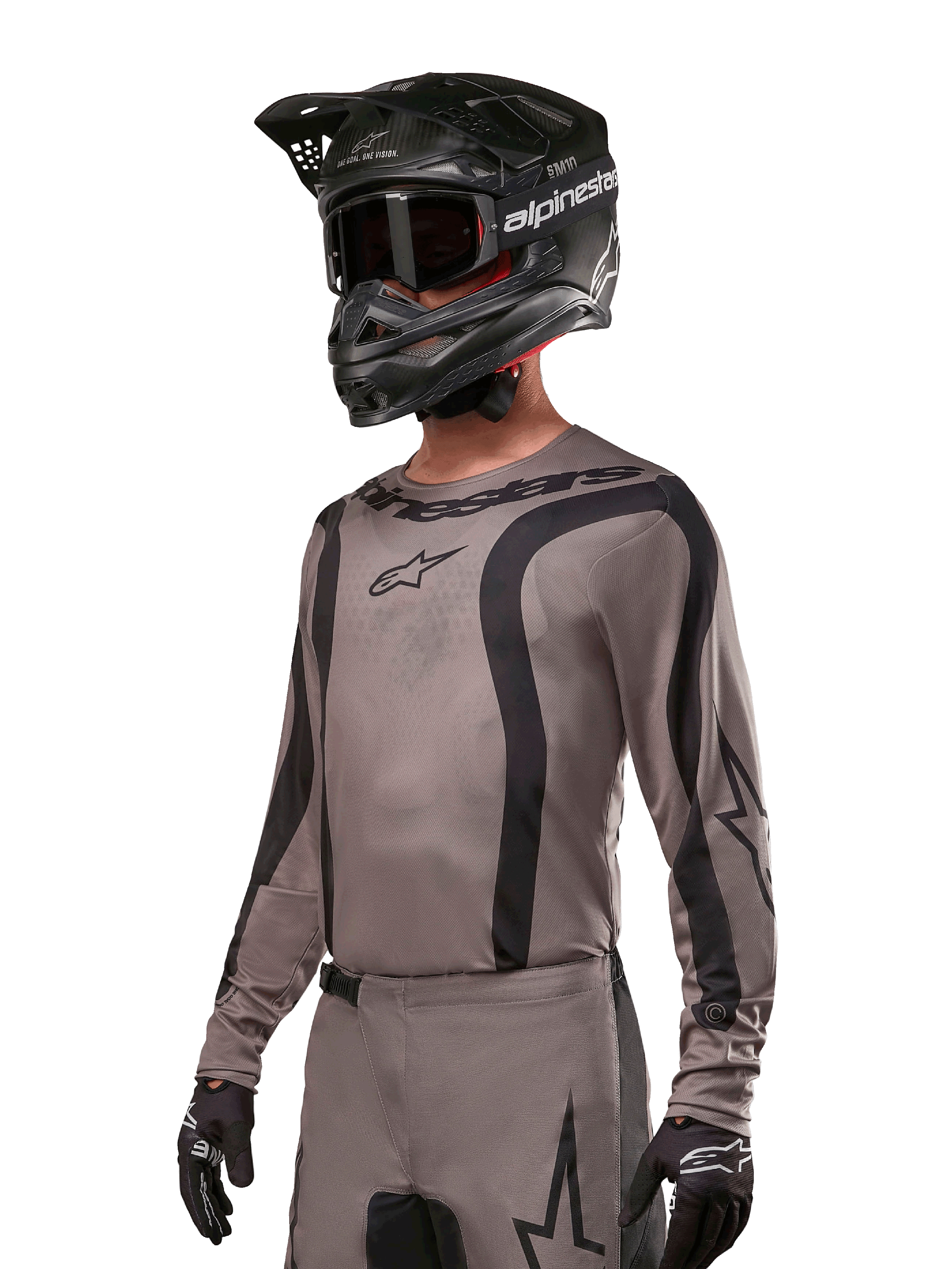 Alpinestars 2024 Fluid Lurv Jersey, motocross shirt, Mud Black en grijs, ontwerp met lange mouwen met gebogen zwarte strepen en logo's, gedragen met bijpassende broek en een zwarte motorcrosshelm, gecoördineerde off-road race-uitrusting
