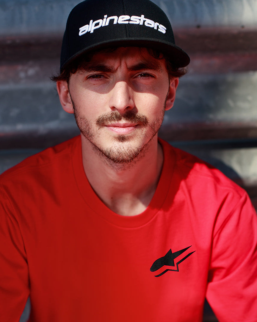 Alpinestars Formulate Csf Tee in rood, Francesco Bagnaia draagt een T-shirt met korte mouwen met zwart Astars-logo en zwarte baseballcap, casual motorsport streetwear