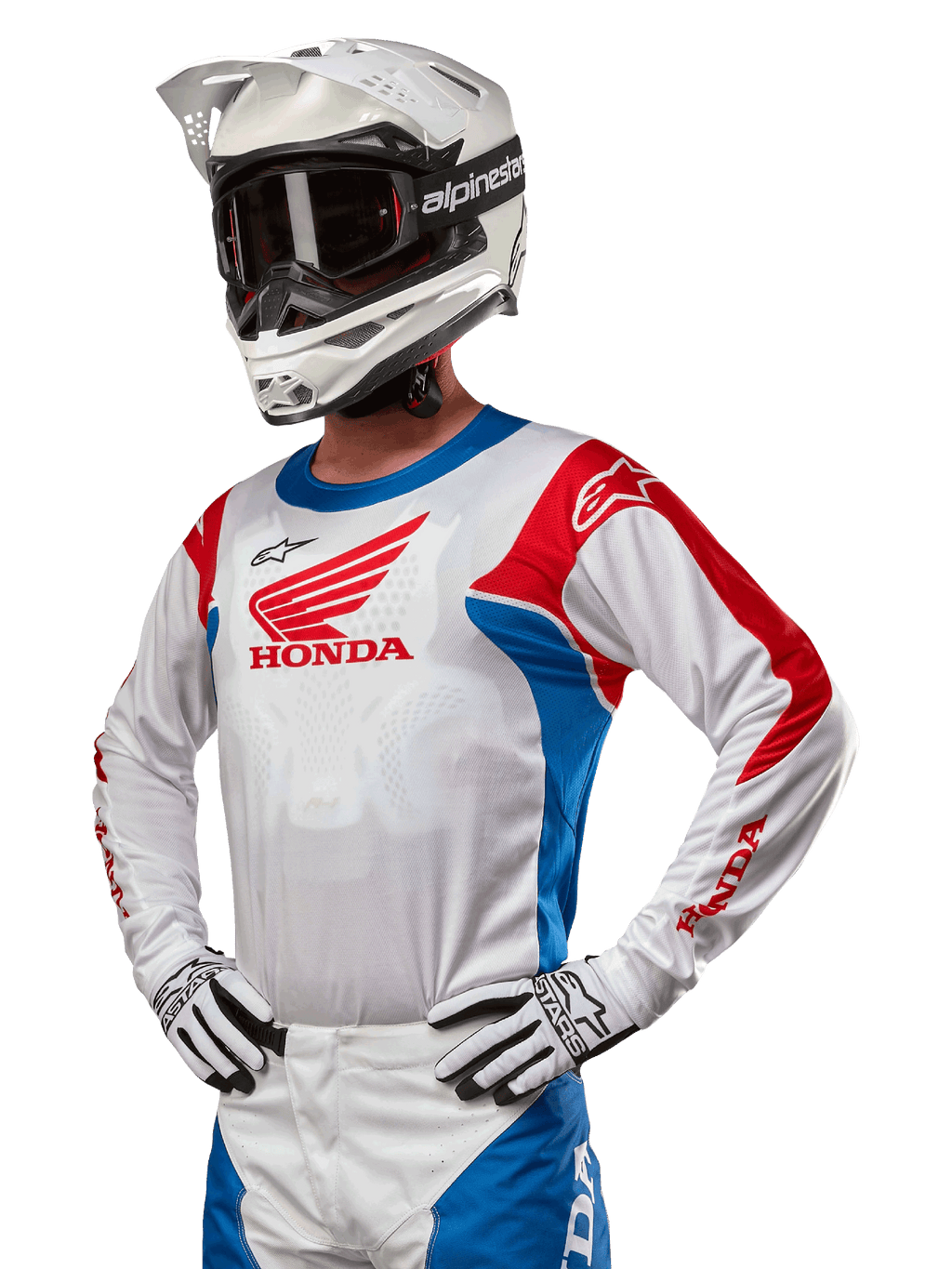 Motorcrossrijder die de Honda Racer Iconic Jersey draagt in wit, felblauw en felrood, met een groot Honda-vleugellogo op de borst, gecombineerd met een witte Alpinestars-helm en bijpassende wit-zwarte handschoenen, gecoördineerde uitrusting voor off-road prestaties