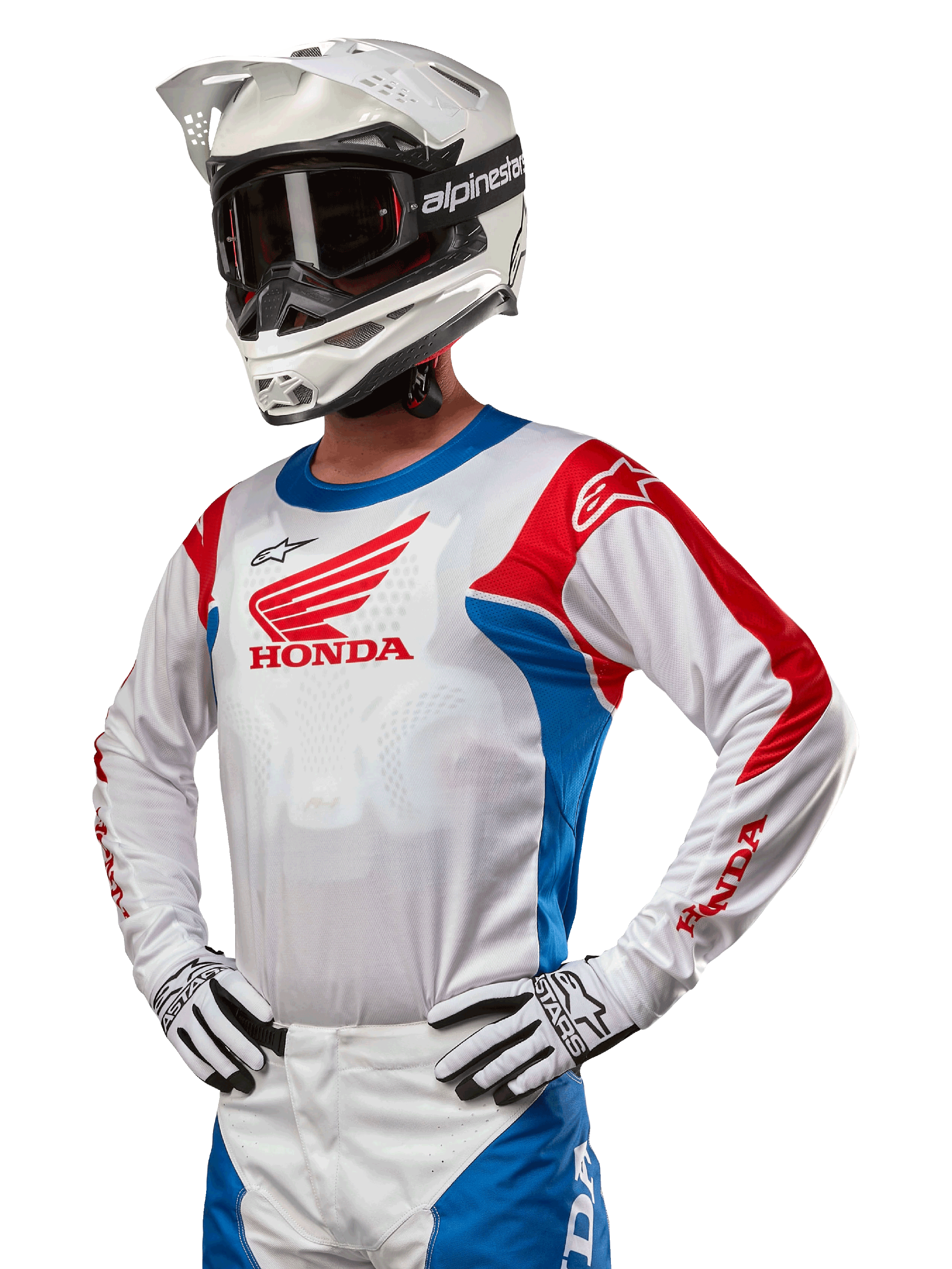 Motorcrossrijder die de Honda Racer Iconic Jersey draagt in wit, felblauw en felrood, met een groot Honda-vleugellogo op de borst, gecombineerd met een witte Alpinestars-helm en bijpassende wit-zwarte handschoenen, gecoördineerde uitrusting voor off-road prestaties