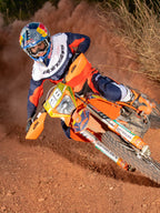 Enduro-rijder in actie op een oranje crossmotor, gekleed in de Alpinestars Pro-Dura Jersey in Navy, Hot Orange en Wit, lichtgewicht en ademend ontwerp met opvallende branding voor off-road prestaties.