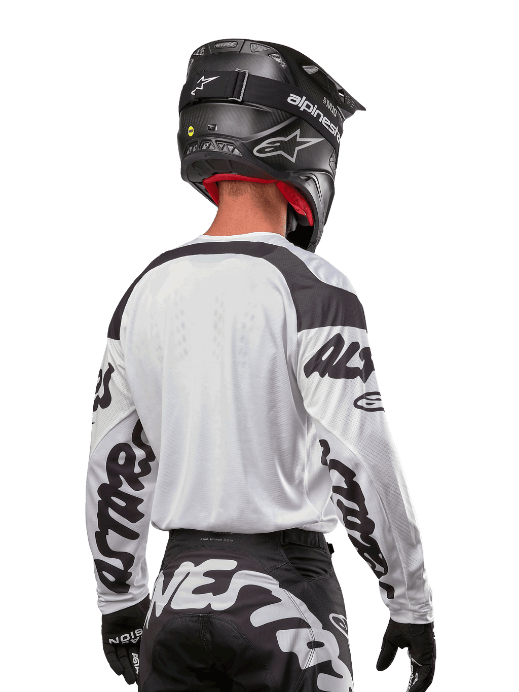 Alpinestars 2024 Racer Hana Jersey, wit en zwart, achteraanzicht met ergonomische pasvorm en opvallende branding op de mouwen, gecombineerd met een zwarte motorcrosshelm en bijpassende zwart-witte broek, hoogwaardige race-uitrusting voor off-road rijden