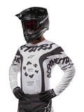 Alpinestars 2024 Racer Hana Jersey, motorcross raceshirt, wit met zwart, opvallende graphics met Alpinestars- en Astars-branding, gedragen met zwarte helm en zwarte handschoenen, performance off-road MX-kleding