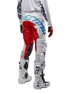 Alpinestars 2024 Racer Hana crossbroek, motorcrossbroek, wit multicolor met rode en blauwe accenten, achteraanzicht met grote branding op het zitvlak, gedragen met wit-zwarte motorcrosslaarzen, ontworpen voor off-road prestaties en duurzaamheid