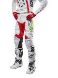 Alpinestars 2024 Racer Hana broek, motorcross racebroek, wit met rode, blauwe en limoengroene accenten, beschermend ontwerp met leren kniepanelen, gedragen met bijpassende jersey, rode handschoenen en witte laarzen met gespen, sportieve motorsportoutfit