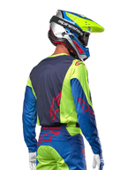 Motorcrosser in de Alpinestars 2024 Racer Hoen Jersey in Yellow Fluo en Blue Night Navy, met een rood sterlogo op de rug, bijpassende motorcrossbroek en een gecoördineerde helm, achteraanzicht dat het ergonomische ontwerp voor off-road prestaties toont.
