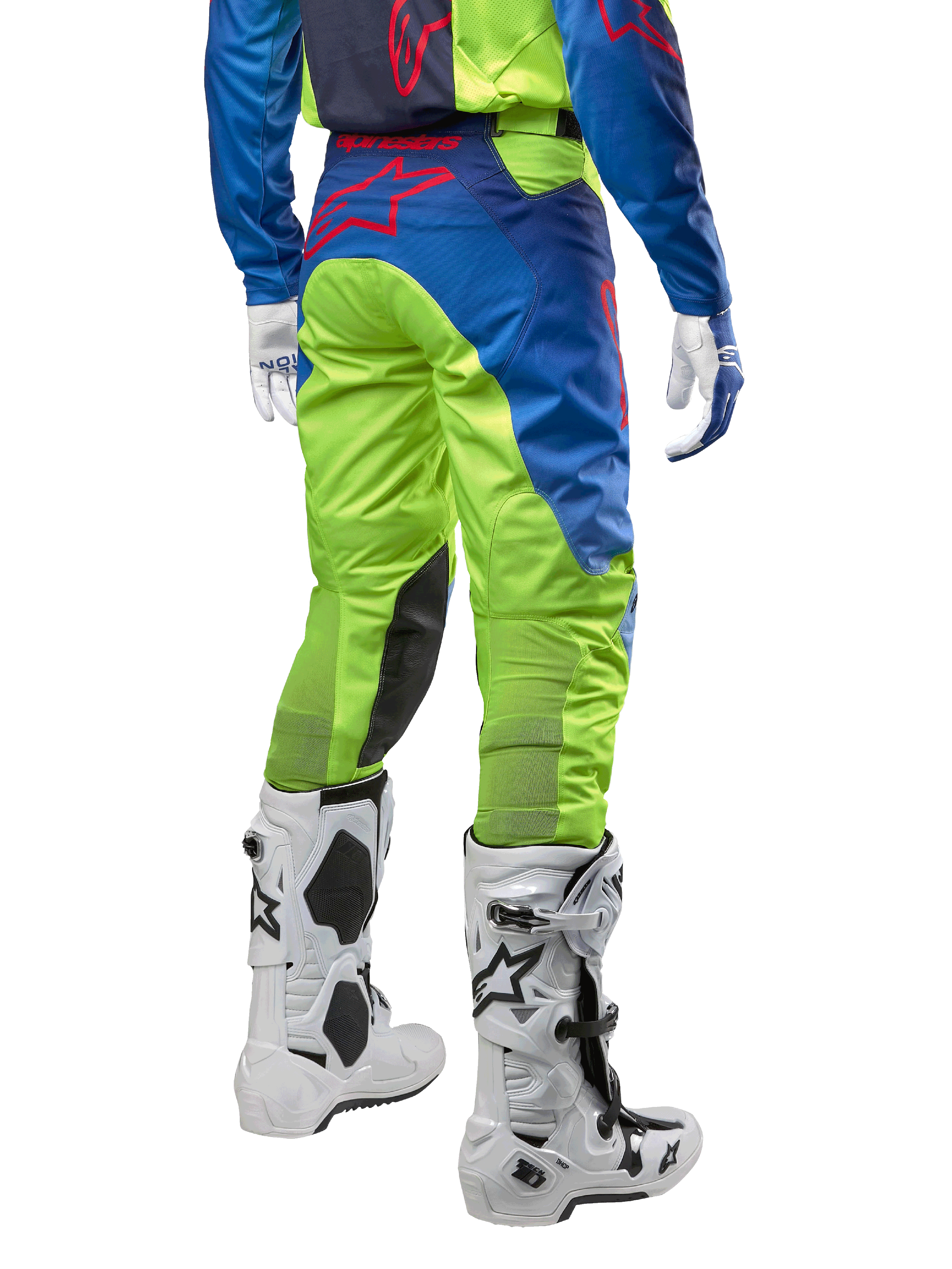 Alpinestars 2024 Racer Hoen crossbroek, motorcross broek, fluoriserend geel en donkerblauw (Blue Night Navy), achteraanzicht, voorzien van een rood Alpinestars-logo, gedragen met bijpassende jersey, witte handschoenen en witte motorcrosslaarzen, duurzaam textiel voor off-road racing