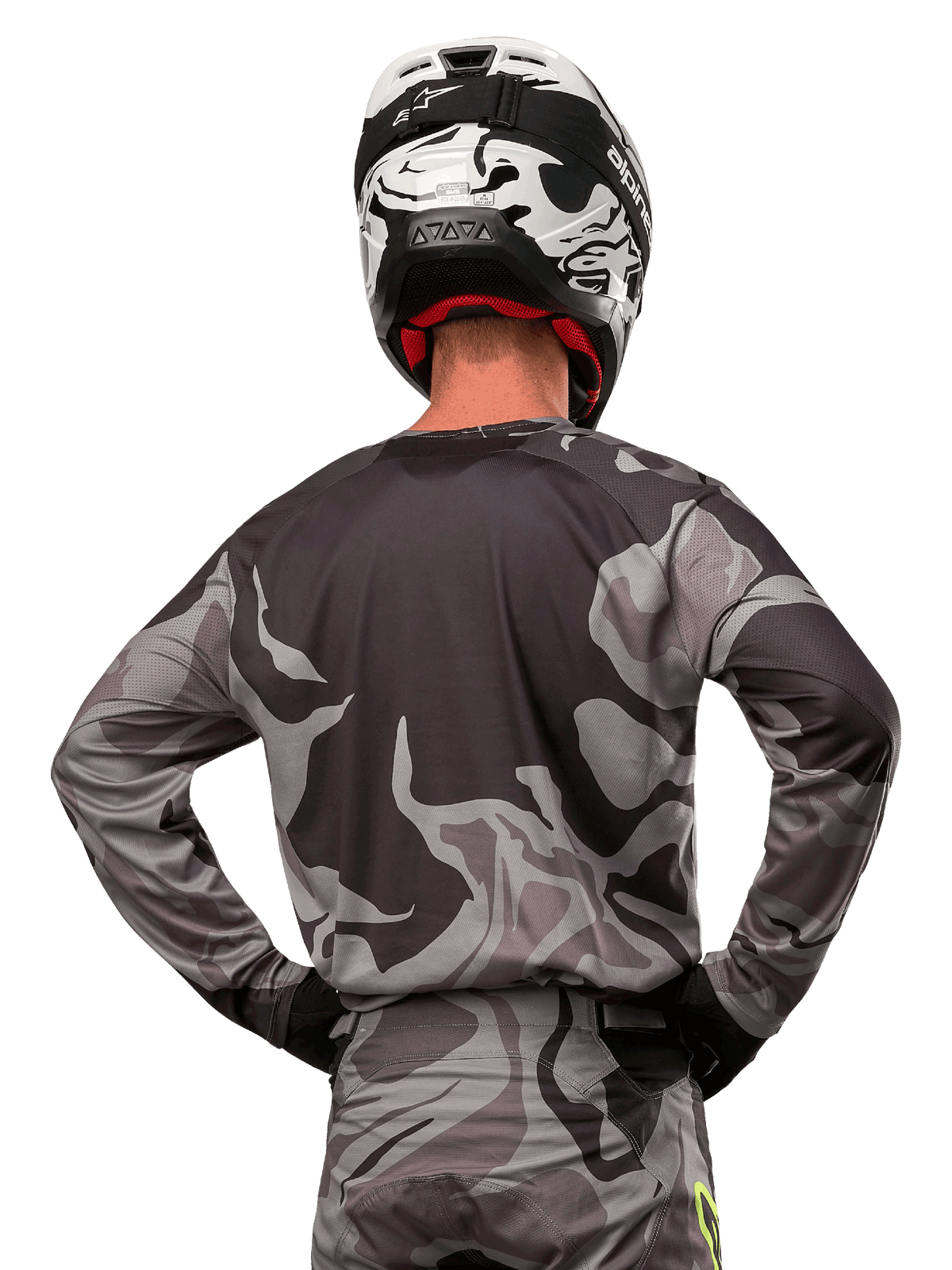 Alpinestars 2024 Racer Tactical Jersey, motorcross shirt, Cast Gray Camo Magnet, achteraanzicht met grijs en zwart camouflagepatroon, gedragen met bijpassende broek en een zwart-witte helm, professionele off-road race-uitrusting