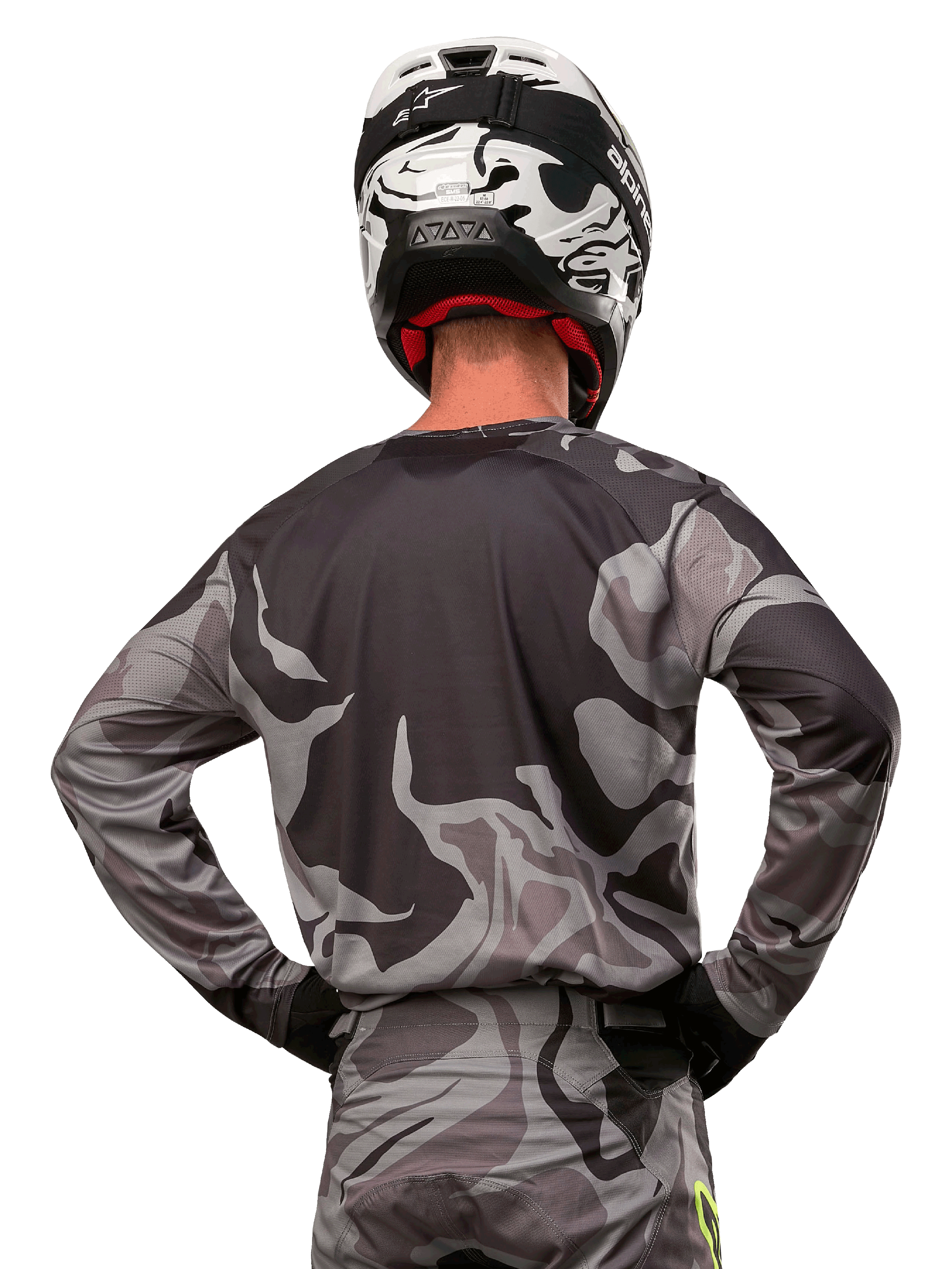 Alpinestars 2024 Racer Tactical Jersey, motorcross shirt, Cast Gray Camo Magnet, achteraanzicht met grijs en zwart camouflagepatroon, gedragen met bijpassende broek en een zwart-witte helm, professionele off-road race-uitrusting