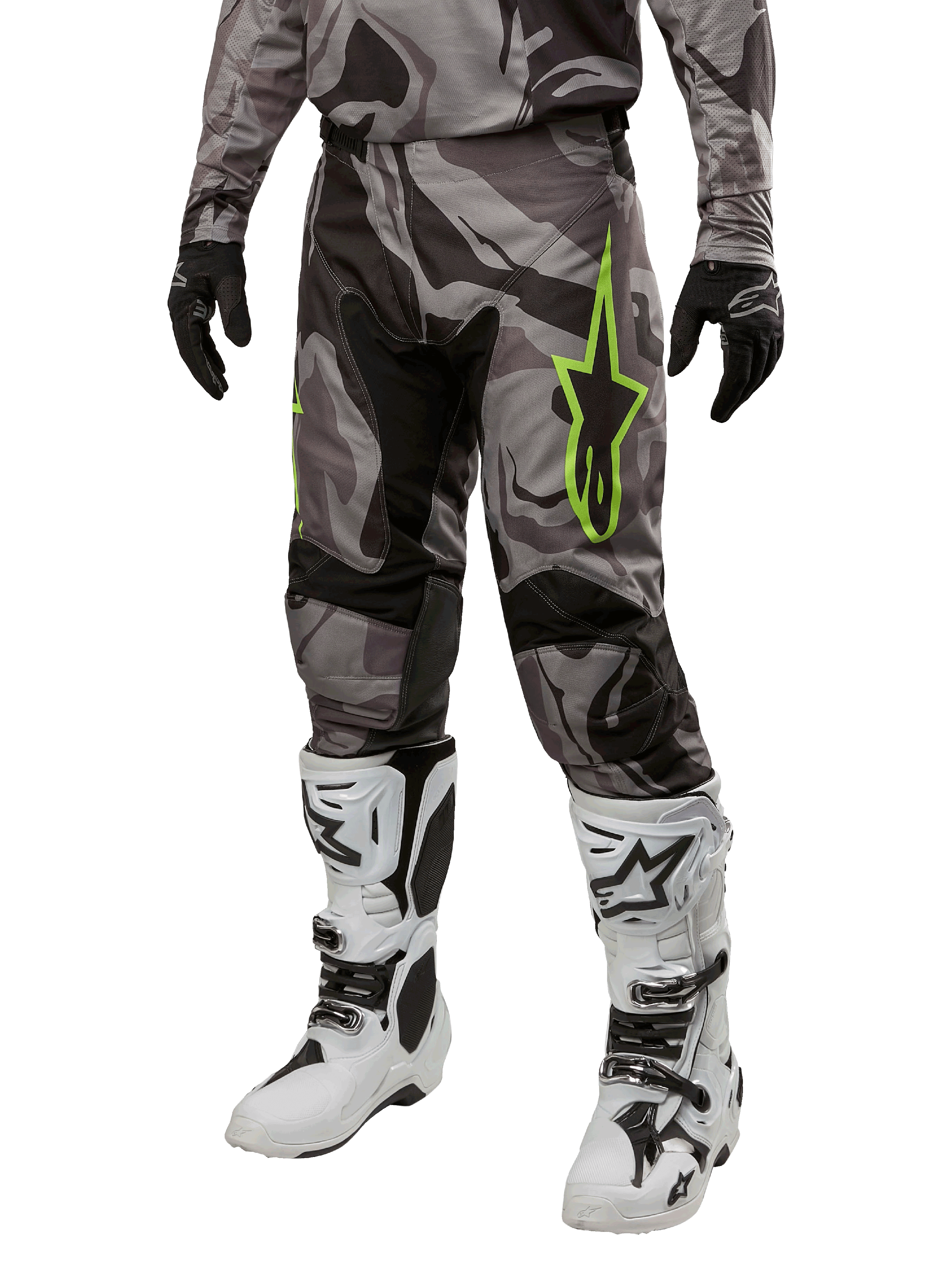 Alpinestars 2024 Racer Tactical broek, motorcrossbroek, grijs en zwart camouflagepatroon, limoengroen sterlogo, gedragen met witte en zwarte laarzen en zwarte handschoenen, off-road motoruitrusting