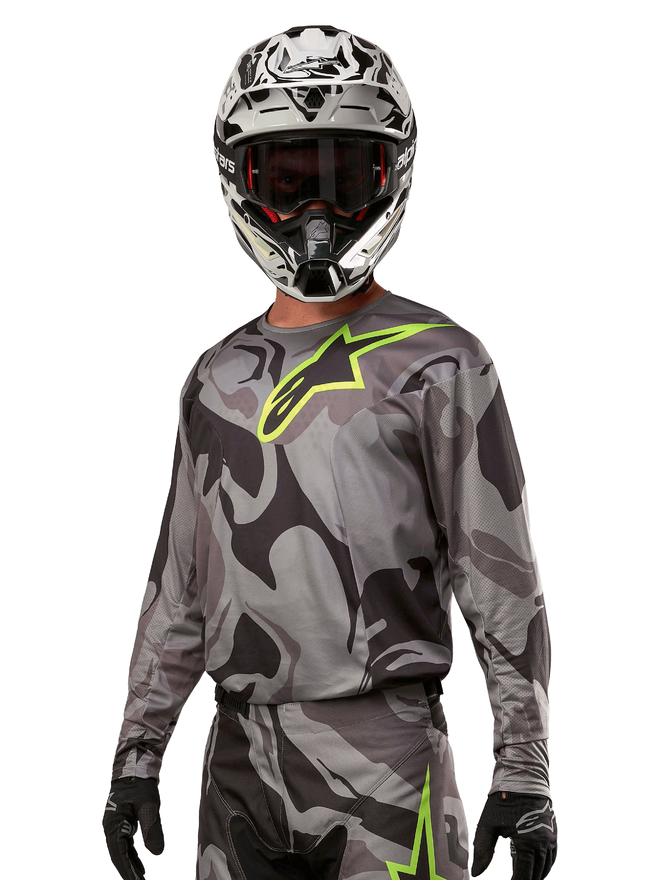 Alpinestars 2024 Racer Tactical Jersey, motorcross shirt, grijs camouflagepatroon met neon groen logo, gedragen met zwart-witte helm en zwarte handschoenen, technische vochtafvoerende stof voor off-road racing