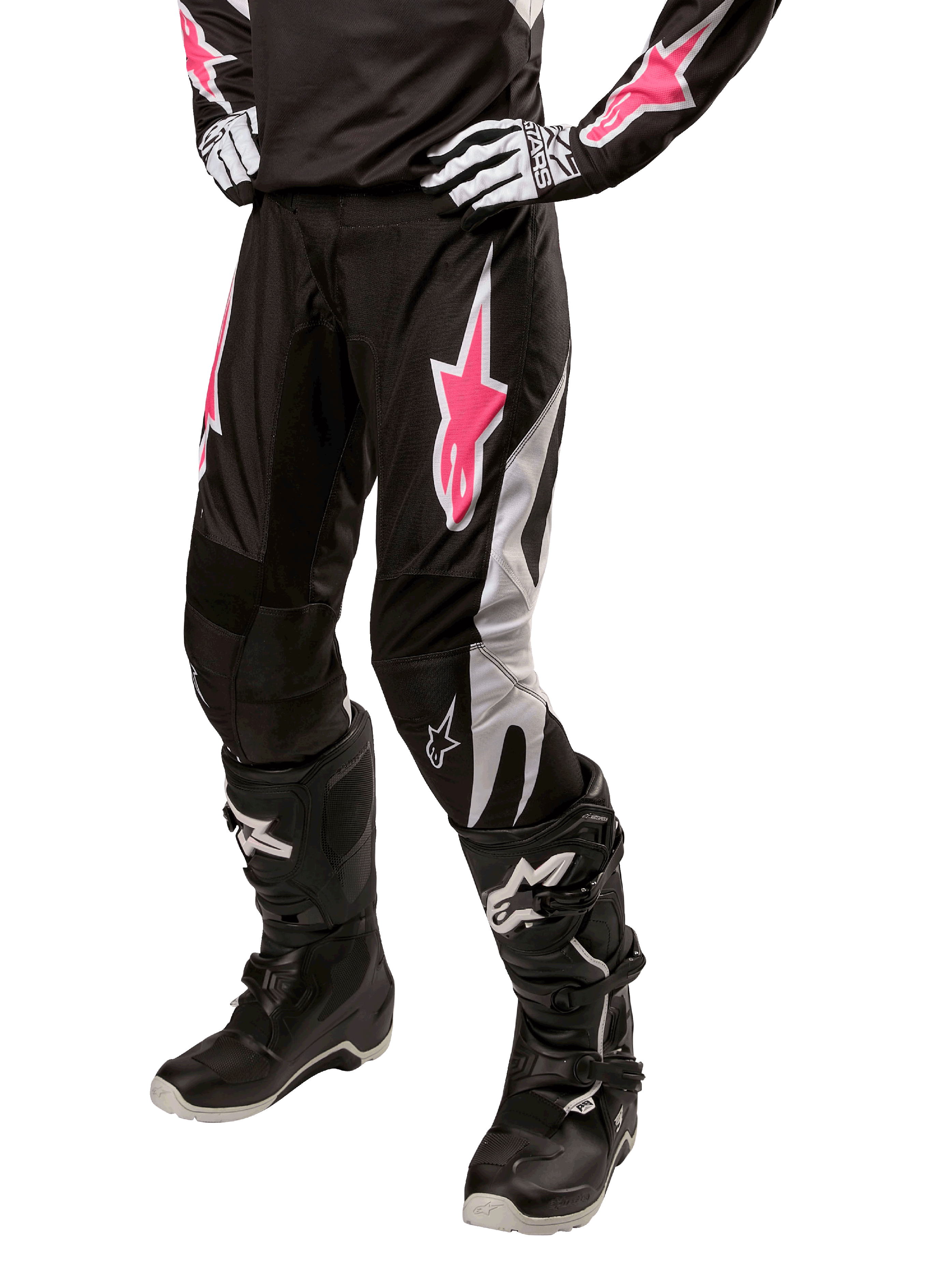 Alpinestars Stella 2024 Fluid dames motorcross broek, zwart en wit met roze accenten, gedragen met bijpassende beschermende uitrusting inclusief laarzen en handschoenen, duurzame flexibele stof voor off-road rijden